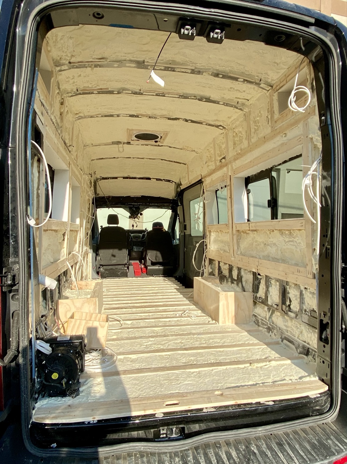 The van interior lined with insulation and plywood, looking toward the cab
