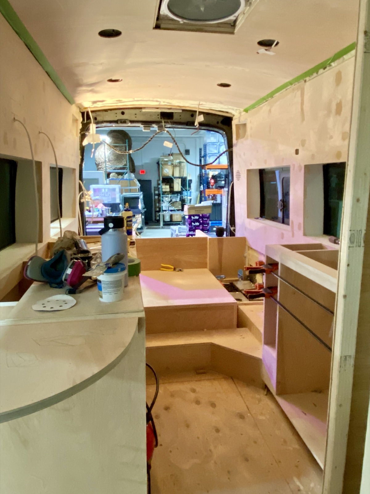 Plywood cabinet boxes along both sides of the van, looking toward the cab