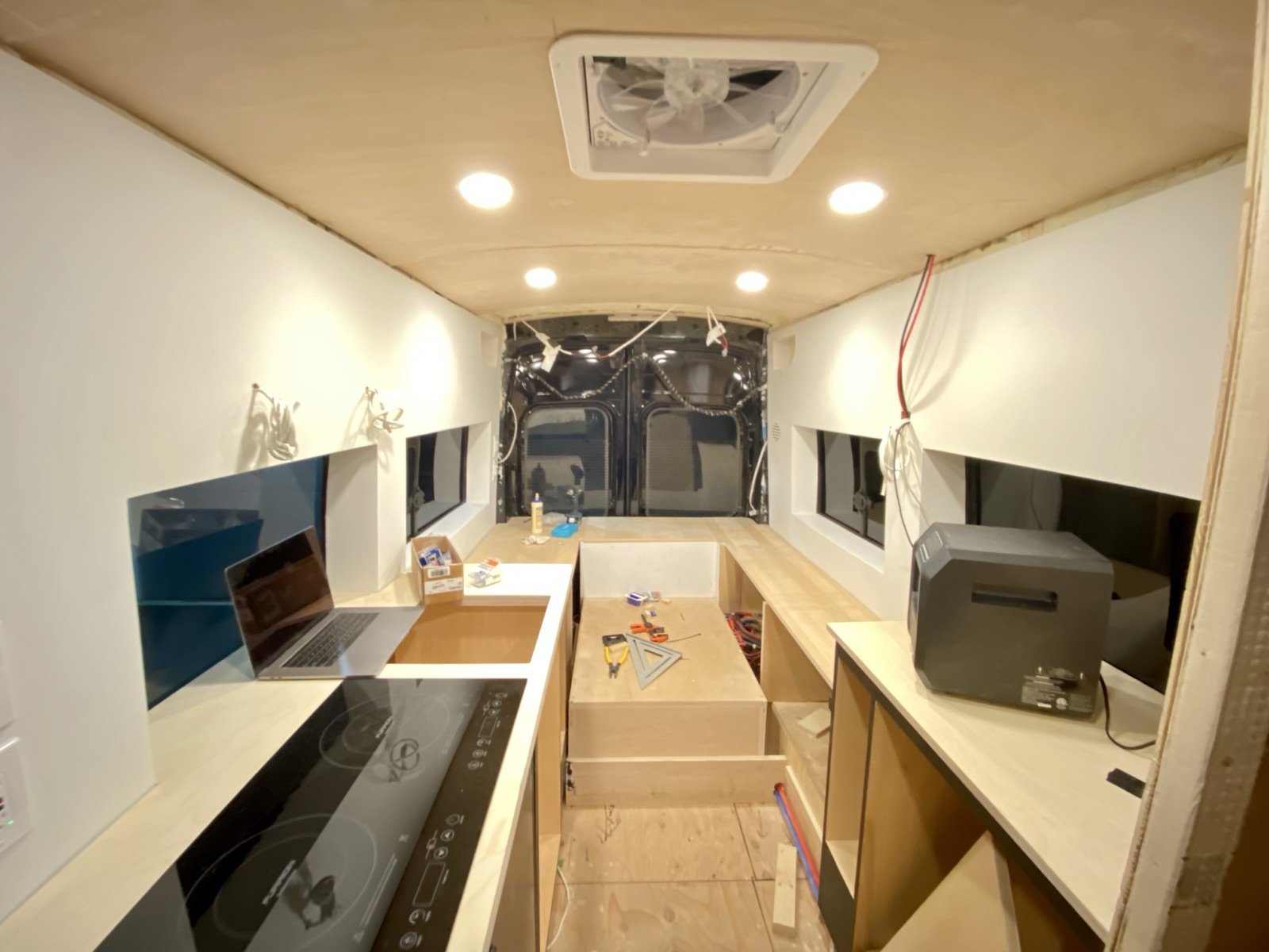 The interior with recessed lights on, the cooktop and bench storage visible