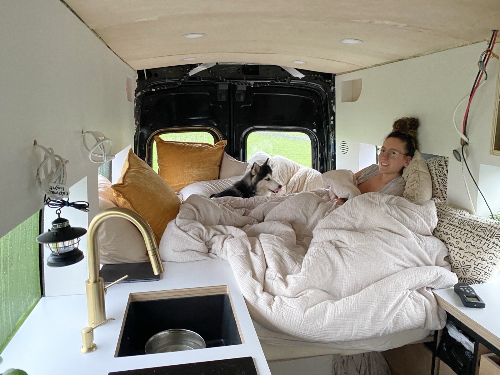 Cristina tucked into a made-up bed in the van with the husky